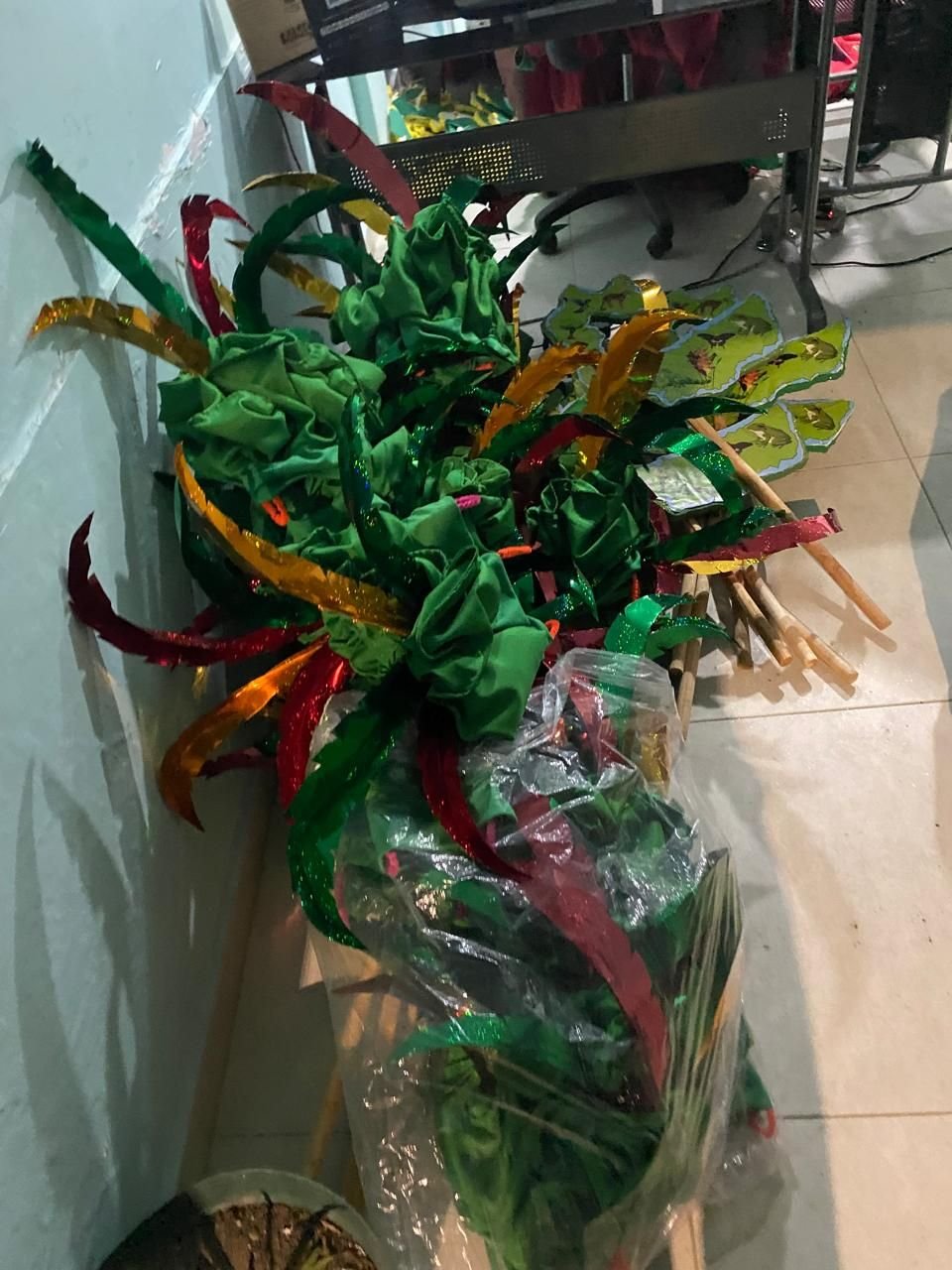 Tocado de tela verde con cintas metálicas rojas, doradas y verdes, listo para un desfile.